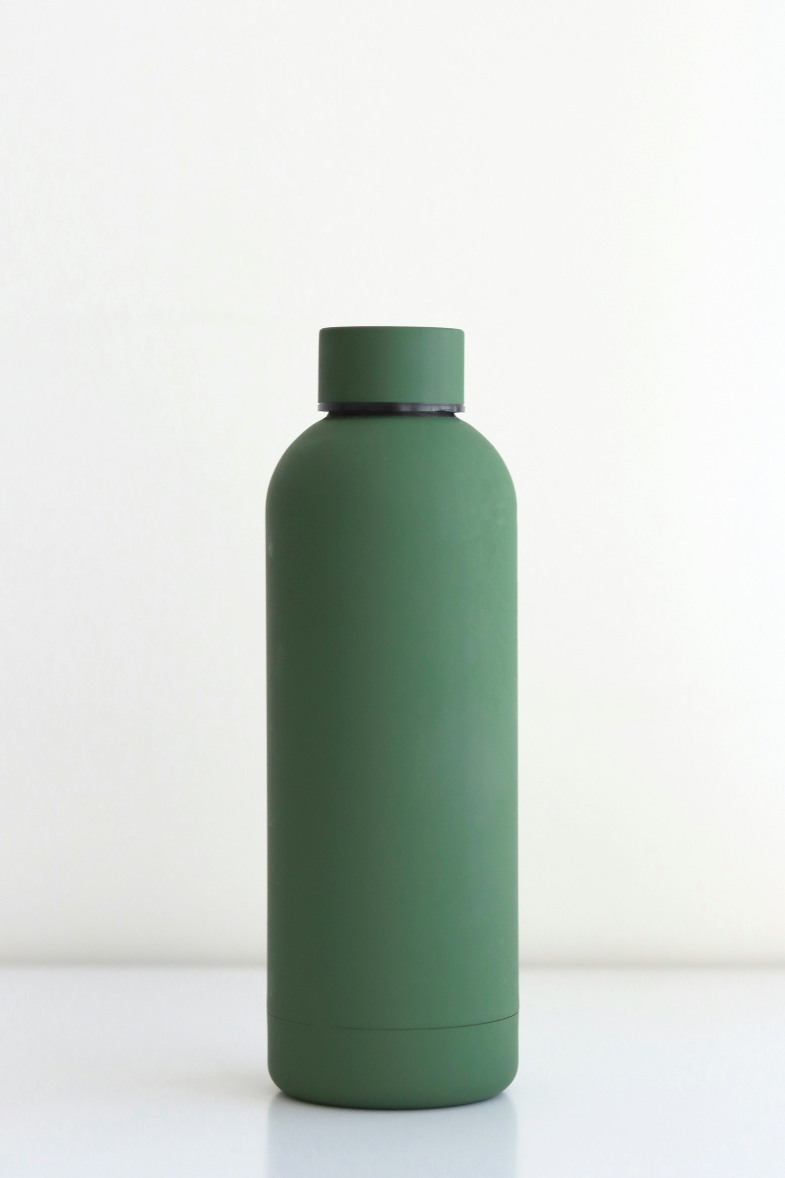 A reusable water bottle beside a commuter bag in natural light